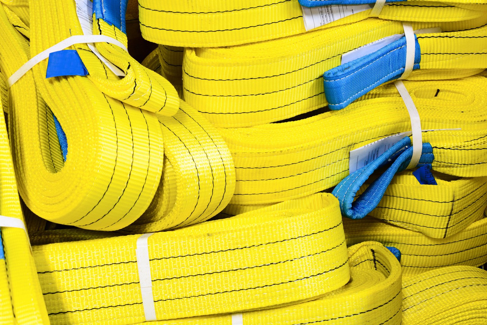 Yellow nylon soft lifting slings stacked in piles. Warehouse of finished products for industrial enterprises